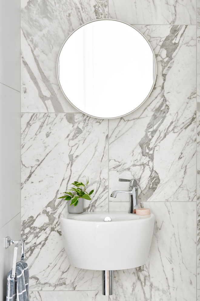 Foto på ett funkis toalett, med vit kakel och ett väggmonterat handfat