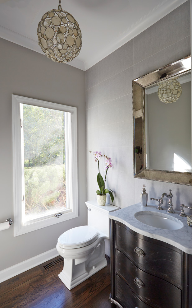 Cette photo montre un WC et toilettes chic en bois foncé avec un lavabo encastré, un plan de toilette en marbre, WC à poser, un carrelage gris, un mur gris et parquet foncé.