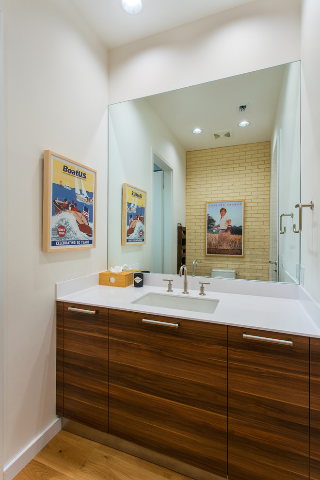 This is an example of a medium sized midcentury cloakroom in Dallas with flat-panel cabinets, brown cabinets, white walls, light hardwood flooring, a submerged sink, engineered stone worktops, beige floors and white worktops.