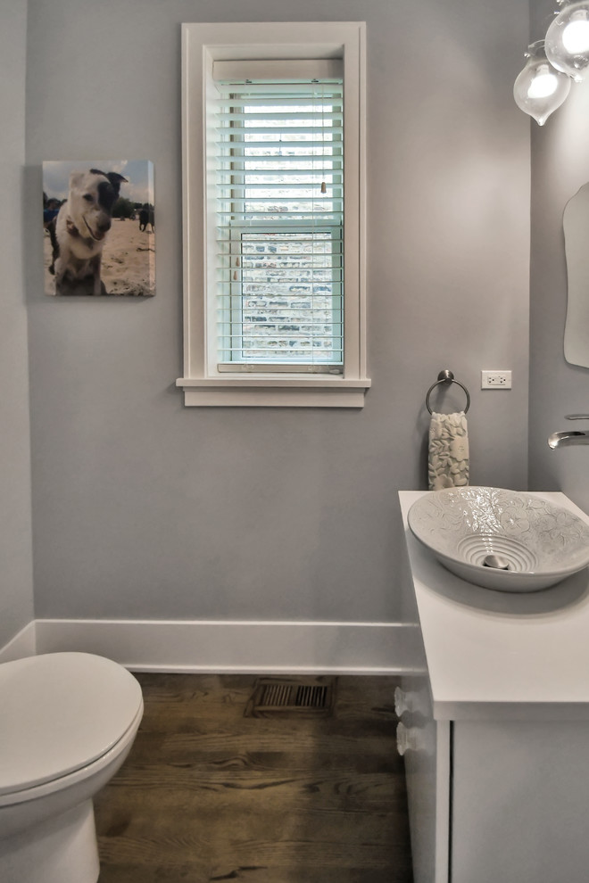 This is an example of a medium sized traditional cloakroom in Chicago with flat-panel cabinets, white cabinets, a one-piece toilet, grey walls, dark hardwood flooring, a vessel sink, engineered stone worktops, brown floors and white worktops.