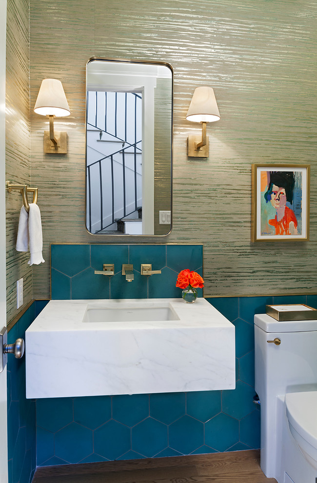 オースティンにあるトランジショナルスタイルのおしゃれなトイレ・洗面所 (一体型トイレ	、青いタイル、ベージュの壁、無垢フローリング、アンダーカウンター洗面器、茶色い床、白い洗面カウンター) の写真