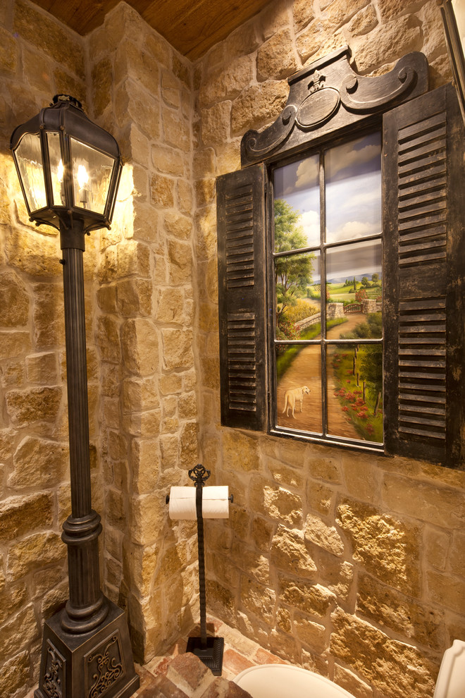 Example of a mid-sized mountain style beige tile and stone tile brick floor powder room design in Dallas with open cabinets, light wood cabinets, a two-piece toilet, beige walls, a vessel sink and wood countertops