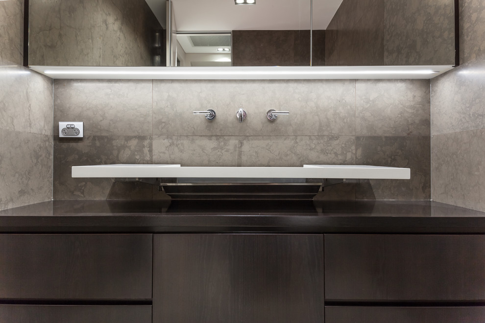 Small modern cloakroom in Sydney with flat-panel cabinets, grey cabinets, grey tiles, travertine tiles, grey walls, travertine flooring, a wall-mounted sink, marble worktops, grey floors and grey worktops.
