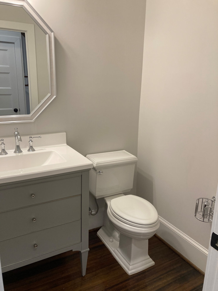 Cette image montre un petit WC et toilettes traditionnel avec un placard en trompe-l'oeil, des portes de placard grises, WC séparés, un mur gris, parquet foncé, un lavabo intégré, un plan de toilette en surface solide, un plan de toilette blanc et meuble-lavabo sur pied.