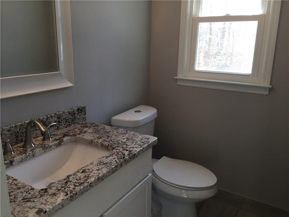 Cette photo montre un petit WC et toilettes chic avec un placard à porte shaker, des portes de placard blanches, WC séparés, un mur gris, un lavabo encastré et un plan de toilette en granite.