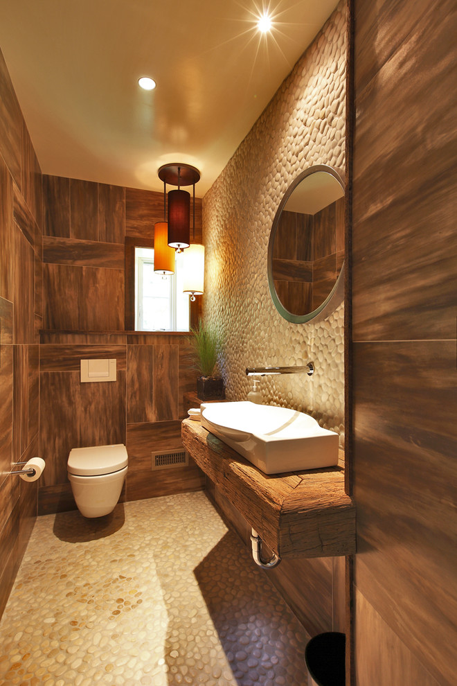 Kleine Rustikale Gästetoilette mit Waschtisch aus Holz, Wandtoilette, beigen Fliesen, Kieselfliesen, Trogwaschbecken und brauner Waschtischplatte in New York