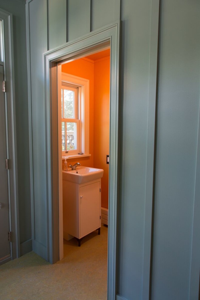 На фото: маленький туалет в стиле неоклассика (современная классика) с плоскими фасадами, белыми фасадами, раздельным унитазом, оранжевыми стенами и монолитной раковиной для на участке и в саду