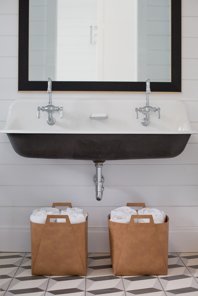 Lantlig inredning av ett litet toalett, med vita väggar, cementgolv, ett väggmonterat handfat och svart golv