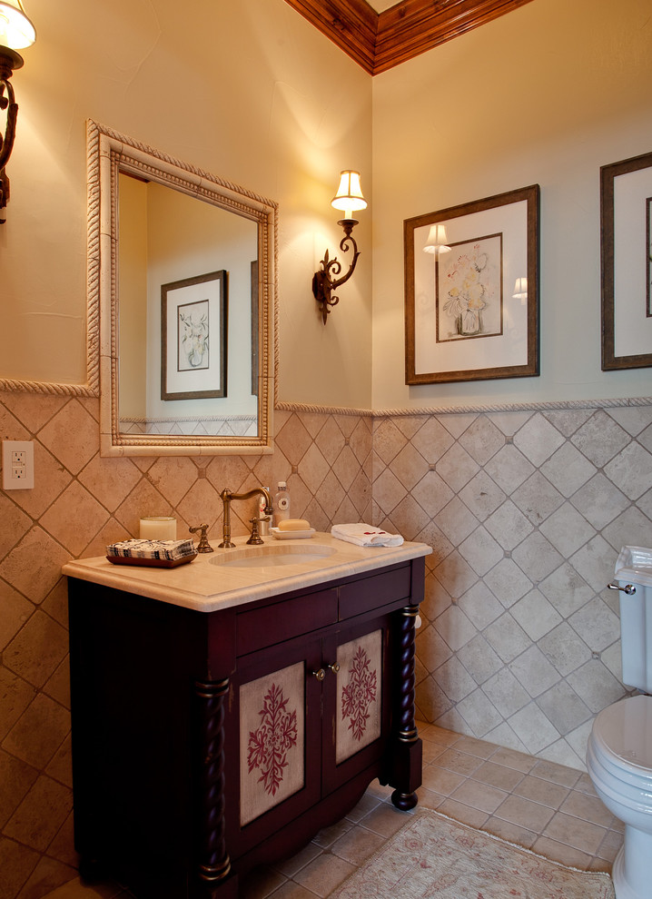 Exemple d'un WC et toilettes chic en bois foncé de taille moyenne avec un placard en trompe-l'oeil, WC séparés, un carrelage beige, un carrelage de pierre, un mur beige, un sol en travertin, un lavabo encastré et un plan de toilette en marbre.