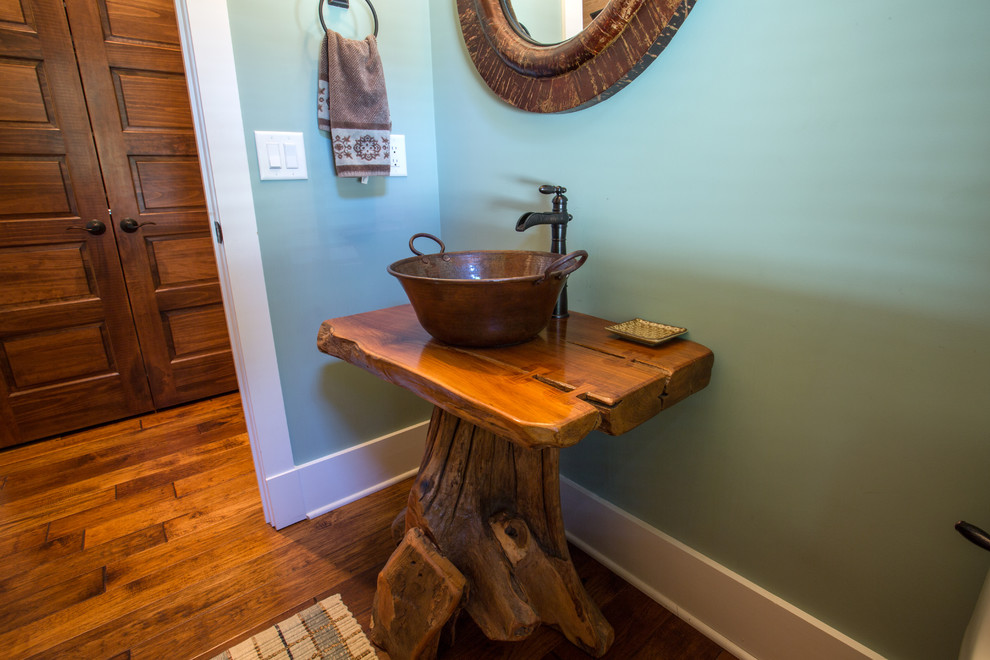 Cette photo montre un WC et toilettes craftsman de taille moyenne avec une vasque, un plan de toilette en bois et un sol en bois brun.