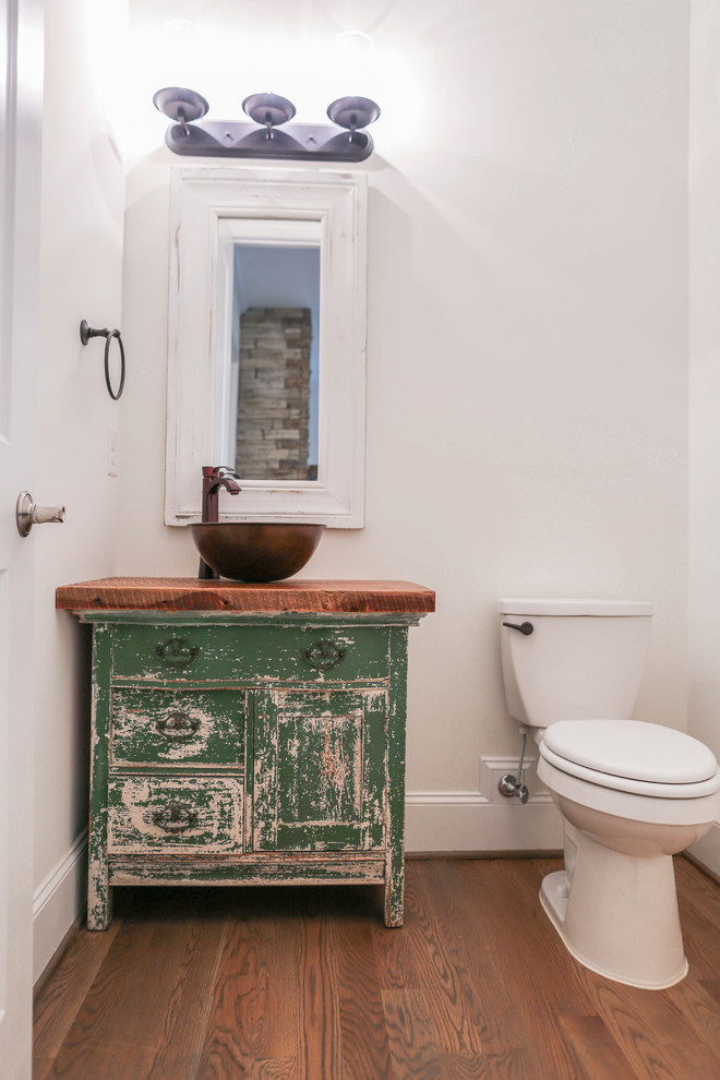 Exemple d'un petit WC et toilettes craftsman avec un placard en trompe-l'oeil, des portes de placards vertess, WC séparés, un mur blanc, parquet clair, une vasque et un plan de toilette en bois.