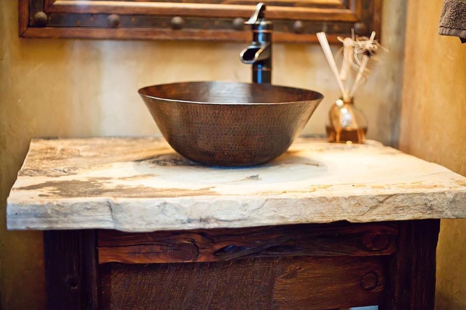 This is an example of a small rustic cloakroom in Austin with dark wood cabinets, beige walls, a vessel sink and beige worktops.