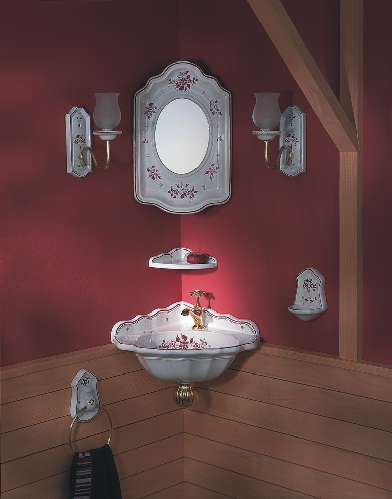 Foto på ett litet lantligt toalett, med ett väggmonterat handfat och röda väggar