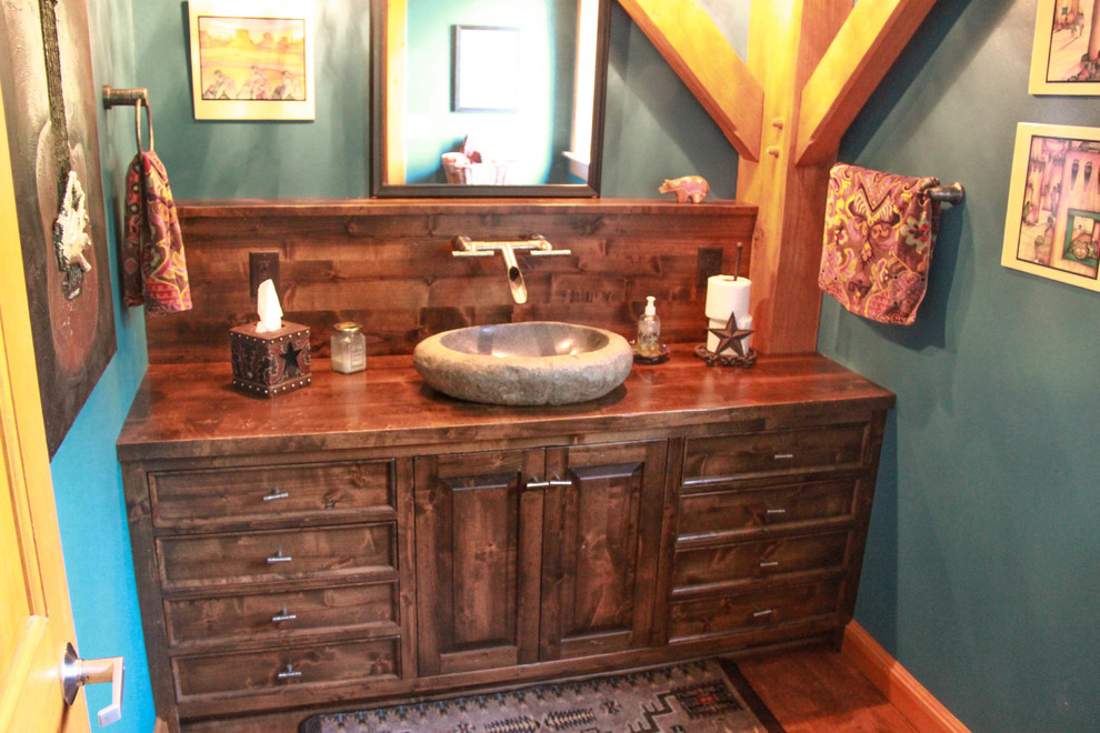 This is an example of a medium sized rustic cloakroom in Milwaukee with freestanding cabinets, medium wood cabinets, a two-piece toilet, medium hardwood flooring, a vessel sink, wooden worktops, green walls, brown floors and brown worktops.