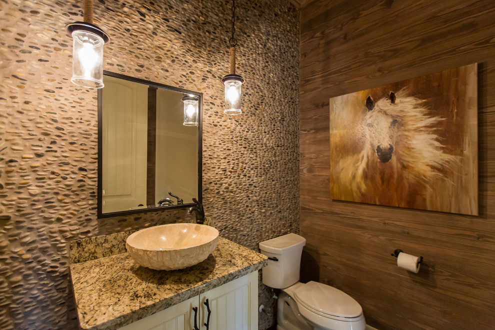 Mittelgroße Rustikale Gästetoilette mit Lamellenschränken, weißen Schränken, Toilette mit Aufsatzspülkasten, farbigen Fliesen, Kieselfliesen, brauner Wandfarbe, dunklem Holzboden, Aufsatzwaschbecken, Granit-Waschbecken/Waschtisch und braunem Boden in Houston