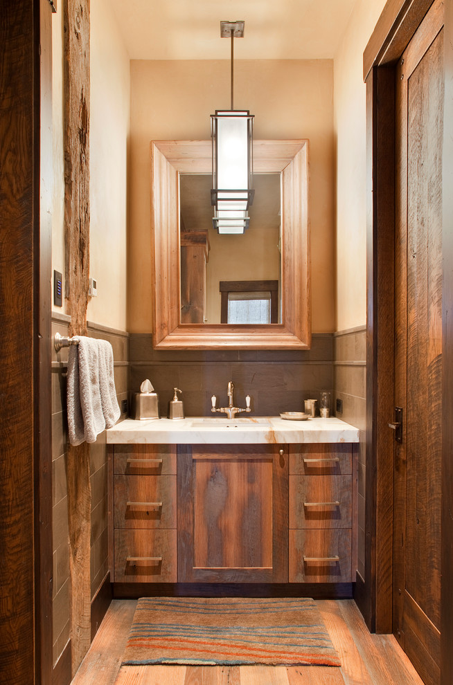 デンバーにある小さなラスティックスタイルのおしゃれなトイレ・洗面所 (中間色木目調キャビネット、無垢フローリング、アンダーカウンター洗面器、ライムストーンタイル) の写真