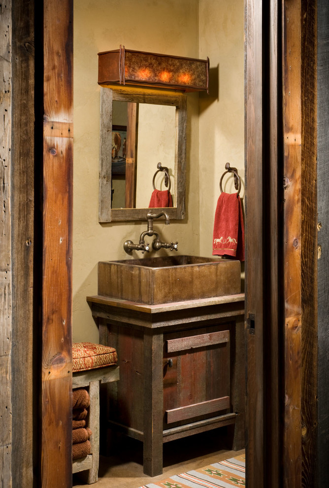 Kleine Urige Gästetoilette mit Aufsatzwaschbecken, verzierten Schränken, dunklen Holzschränken, Waschtisch aus Holz, beiger Wandfarbe und brauner Waschtischplatte in Sonstige