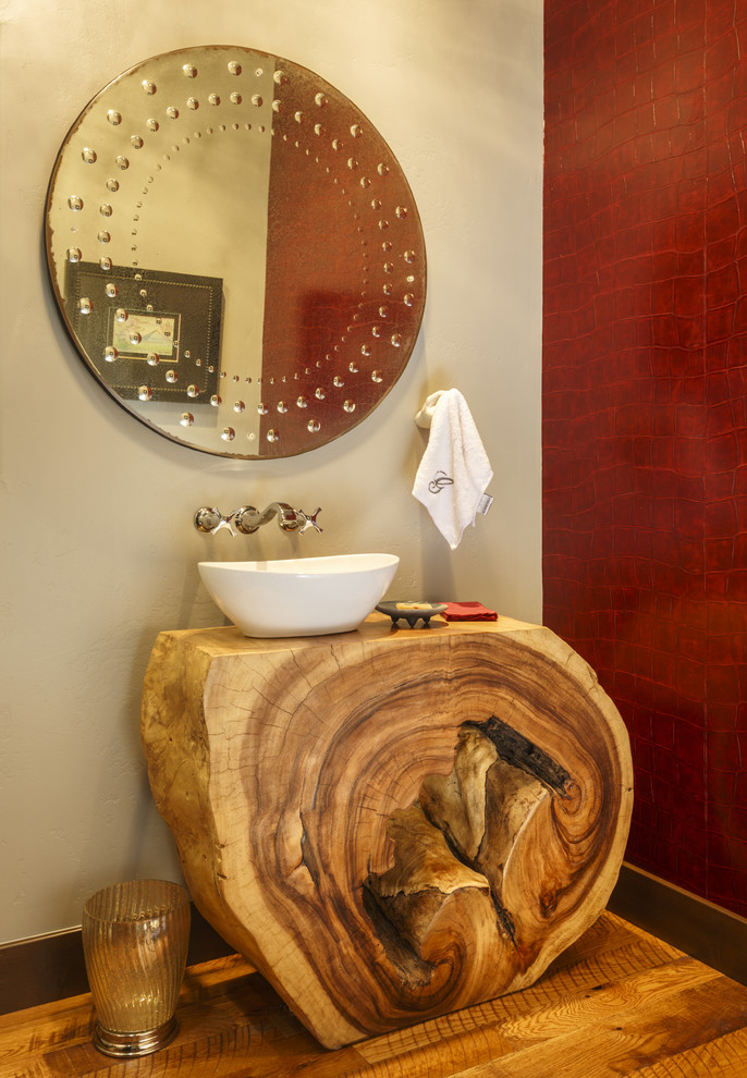 Inredning av ett rustikt toalett, med vita väggar, mörkt trägolv, ett fristående handfat och träbänkskiva