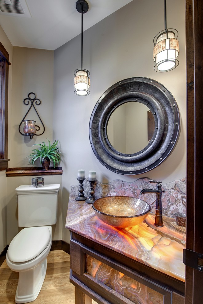 Medelhavsstil inredning av ett flerfärgad flerfärgat toalett, med skåp i mörkt trä, en toalettstol med separat cisternkåpa, röd kakel, bruna väggar, mellanmörkt trägolv och granitbänkskiva