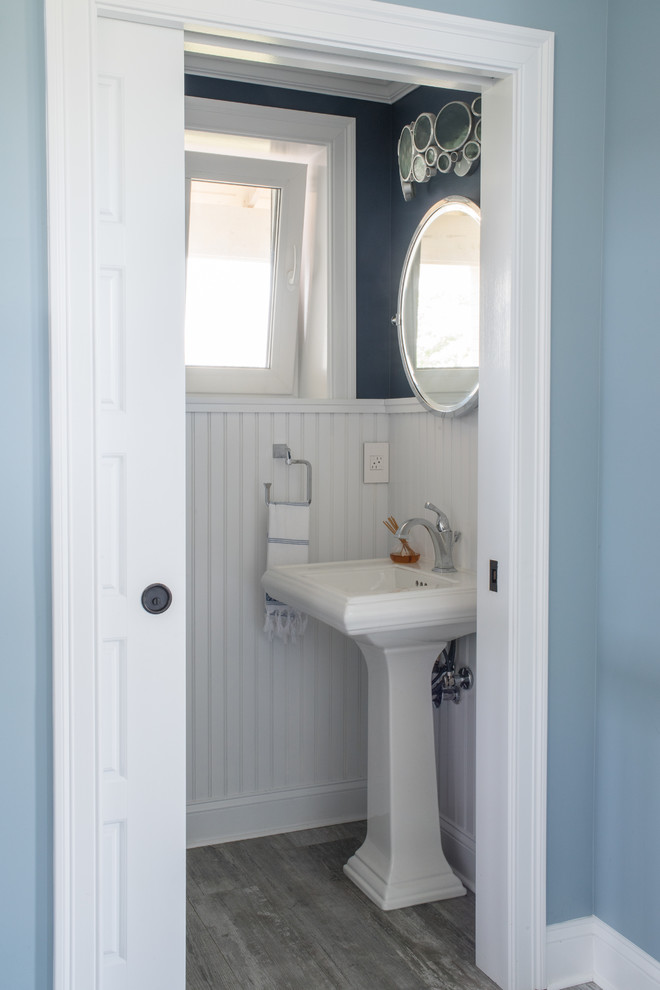 На фото: туалет в стиле неоклассика (современная классика) с раковиной с пьедесталом, синими стенами и деревянным полом с