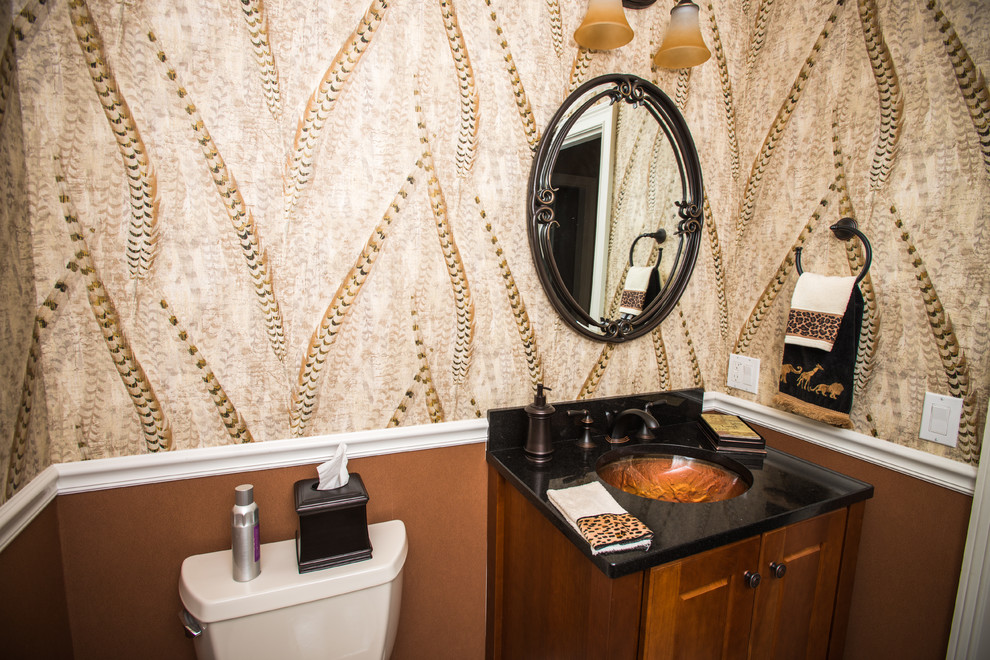 Exemple d'un petit WC et toilettes chic en bois brun avec un placard avec porte à panneau surélevé, un mur marron, un lavabo encastré, un plan de toilette en surface solide et un plan de toilette noir.