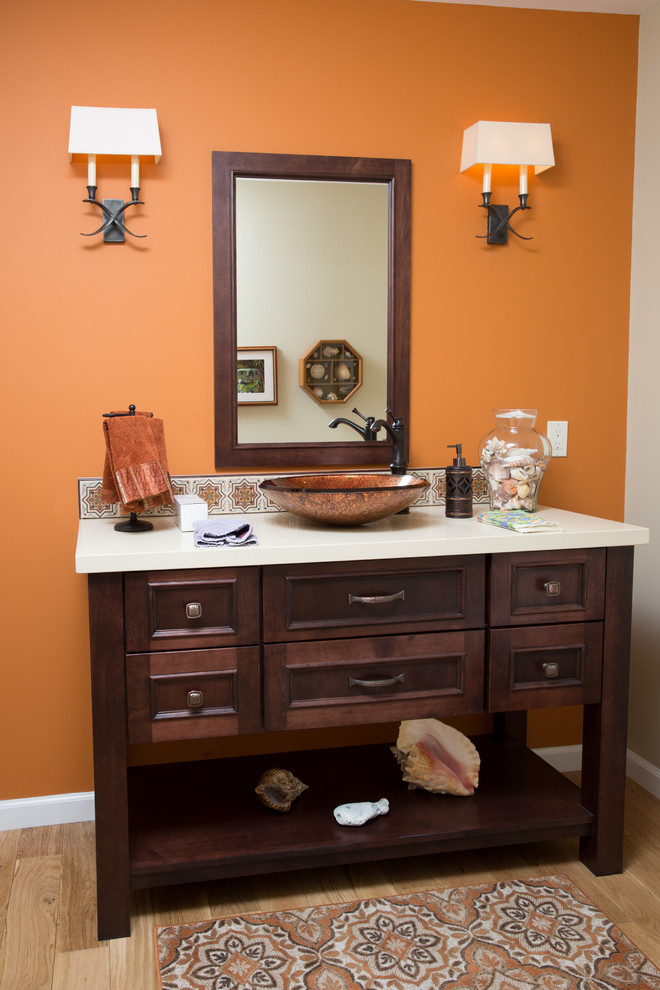 Cette image montre un petit WC et toilettes traditionnel en bois brun avec une vasque, un placard avec porte à panneau encastré, un plan de toilette en quartz modifié, un carrelage multicolore, un mur orange et parquet clair.