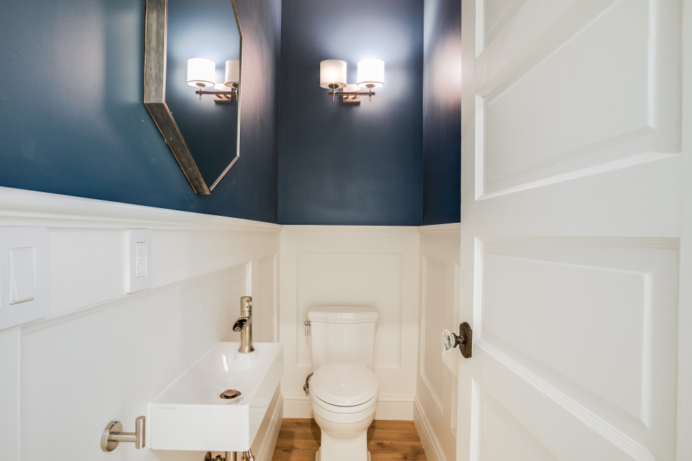 Aménagement d'un WC et toilettes classique avec des portes de placard blanches, un mur bleu, parquet clair, un lavabo suspendu, meuble-lavabo suspendu et boiseries.