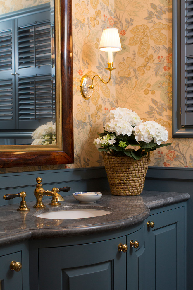 Immagine di un bagno di servizio con ante con bugna sagomata, ante blu, WC monopezzo, pareti multicolore, parquet scuro, lavabo sottopiano, top in marmo, pavimento marrone e top grigio