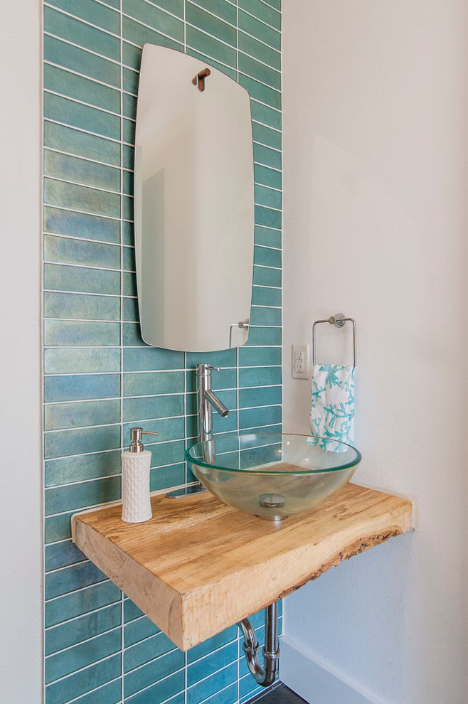 ダラスにあるコンテンポラリースタイルのおしゃれなトイレ・洗面所 (ベッセル式洗面器、木製洗面台、青いタイル、マルチカラーの壁、ブラウンの洗面カウンター) の写真