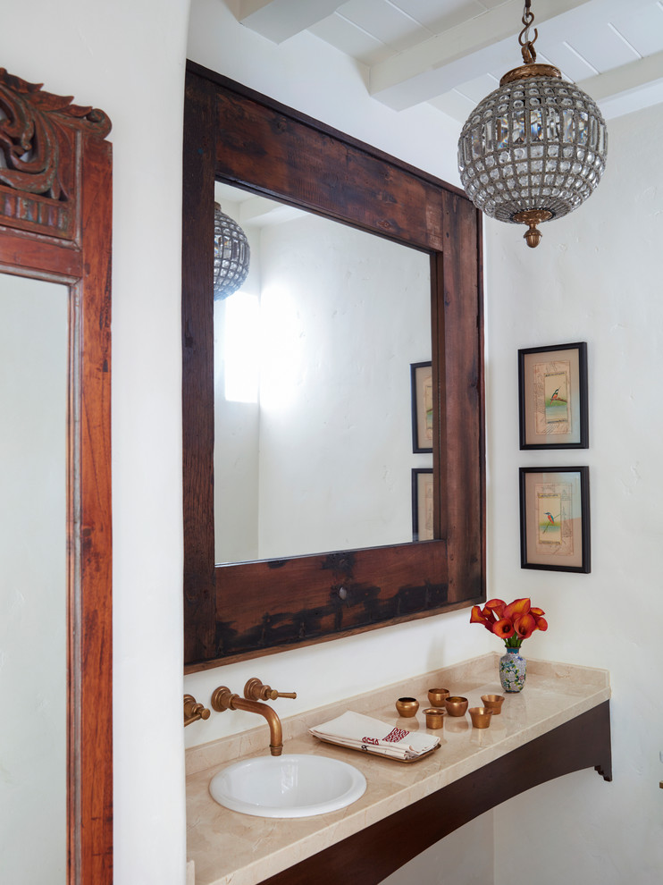 Mediterrane Gästetoilette mit weißer Wandfarbe, Einbauwaschbecken, Kalkstein-Waschbecken/Waschtisch und beiger Waschtischplatte in Los Angeles