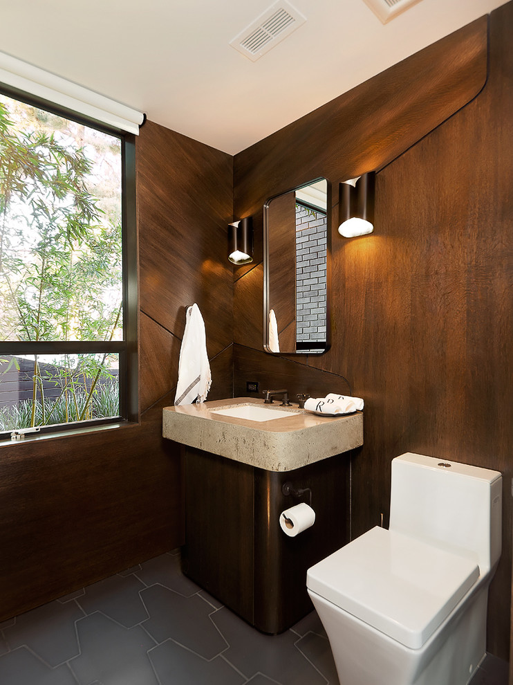 Mittelgroße Moderne Gästetoilette mit dunklen Holzschränken, Toilette mit Aufsatzspülkasten, brauner Wandfarbe, Porzellan-Bodenfliesen, Unterbauwaschbecken, Travertin-Waschtisch, grauem Boden und flächenbündigen Schrankfronten in Los Angeles