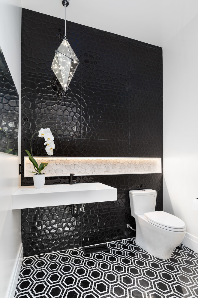 Moderne Gästetoilette mit schwarzen Fliesen, weißer Wandfarbe, Wandwaschbecken, buntem Boden und grauer Waschtischplatte in Sonstige