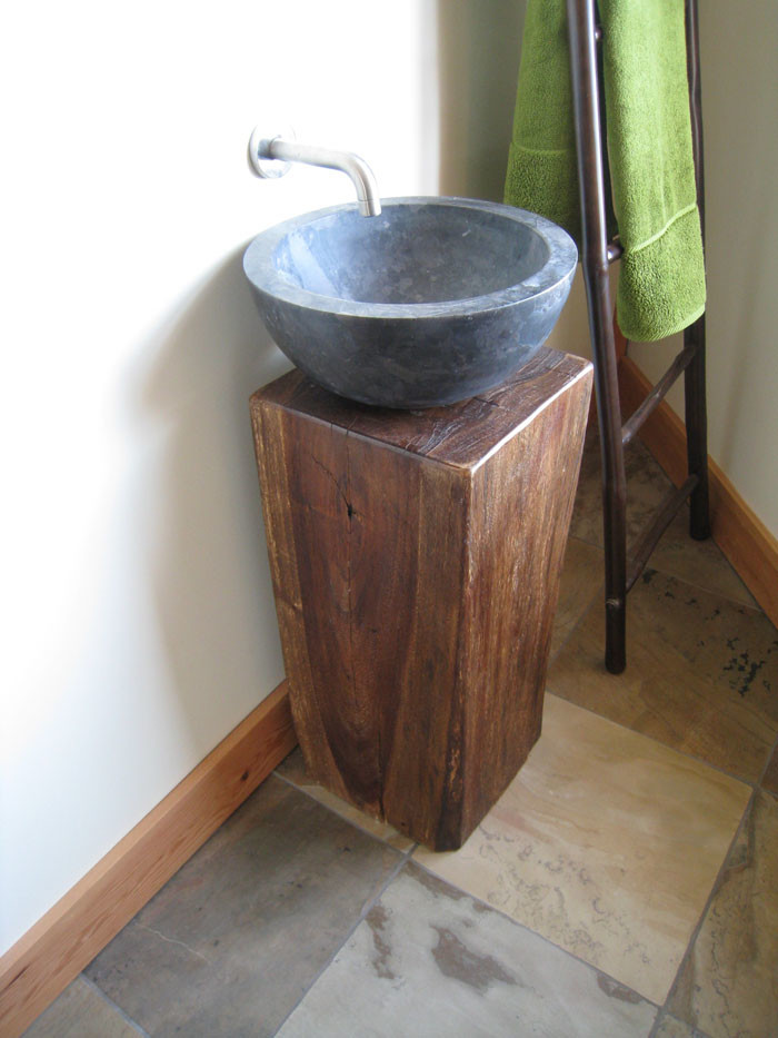 Cette photo montre un petit WC et toilettes tendance en bois clair avec un placard sans porte, un mur blanc, un sol en galet, une vasque, un plan de toilette en bois et un sol multicolore.