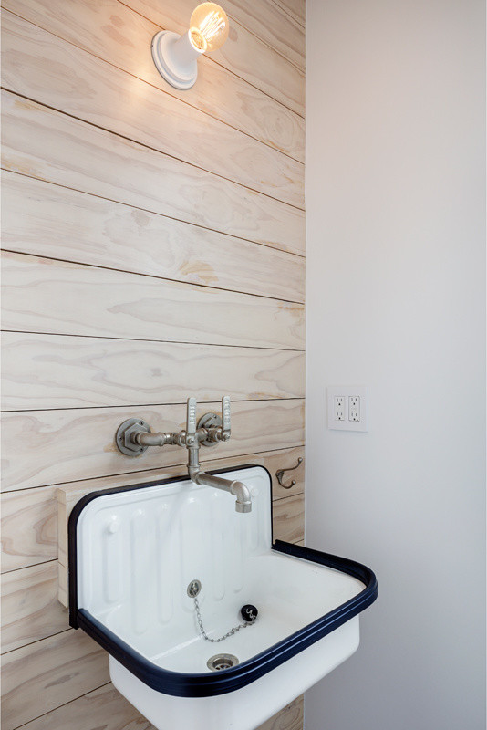 Diseño de aseo nórdico pequeño con paredes blancas, lavabo suspendido y suelo negro