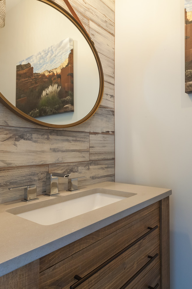 Cette image montre un petit WC et toilettes chalet en bois vieilli avec un placard à porte plane, un mur beige, un sol en bois brun, un lavabo encastré, un plan de toilette en quartz modifié et un sol marron.