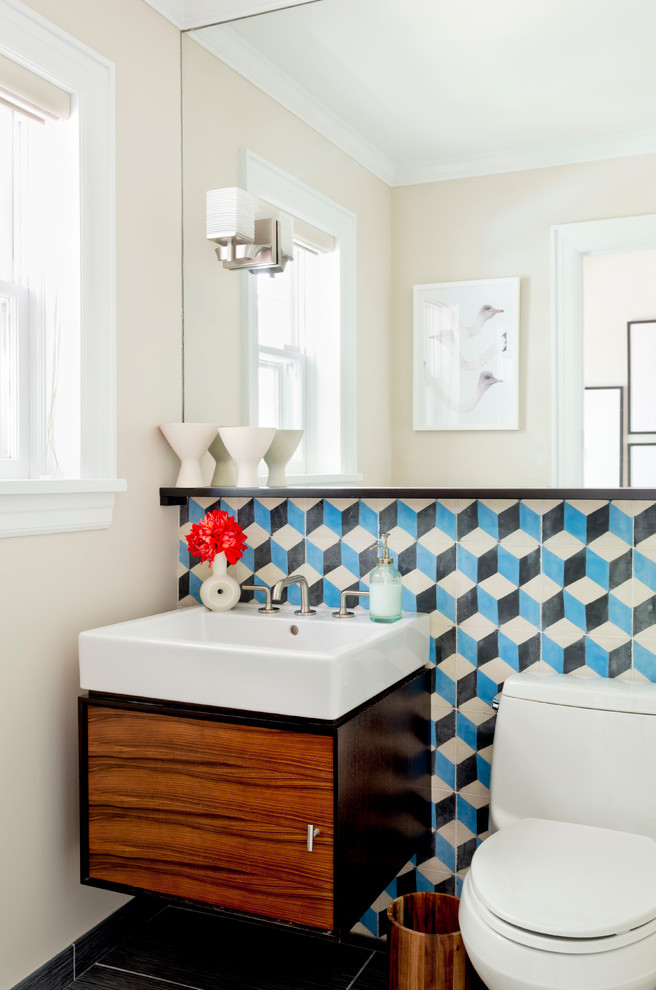 Cette photo montre un petit WC et toilettes éclectique en bois foncé avec un placard à porte plane, WC à poser, un carrelage bleu, des carreaux de béton, un mur beige, un sol en carrelage de porcelaine et un lavabo suspendu.