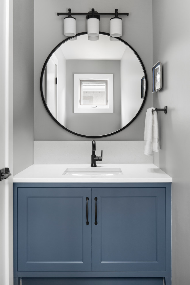 Ejemplo de aseo contemporáneo pequeño con armarios con paneles empotrados, puertas de armario azules, paredes grises, lavabo bajoencimera, encimera de acrílico y encimeras blancas