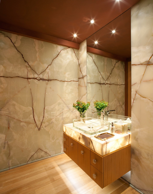 Example of a mid-sized trendy beige tile and stone slab bamboo floor and beige floor powder room design in Tampa with flat-panel cabinets, medium tone wood cabinets, multicolored walls, a vessel sink and onyx countertops