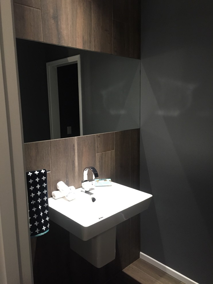На фото: туалет среднего размера в стиле модернизм с подвесной раковиной, коричневой плиткой, керамической плиткой, черными стенами и полом из керамической плитки с