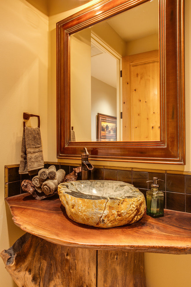 シアトルにある小さなラスティックスタイルのおしゃれなトイレ・洗面所 (ベッセル式洗面器、木製洗面台、黄色い壁、ブラウンの洗面カウンター) の写真