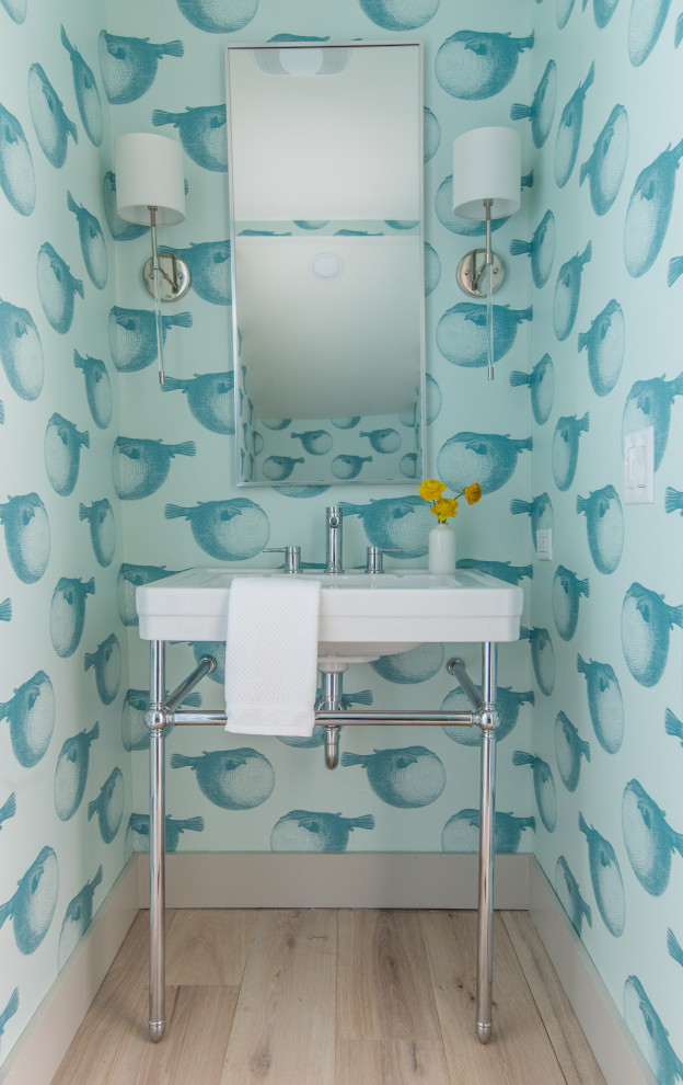This is an example of a beach style cloakroom in Jacksonville with blue walls, light hardwood flooring, a console sink, beige floors and wallpapered walls.