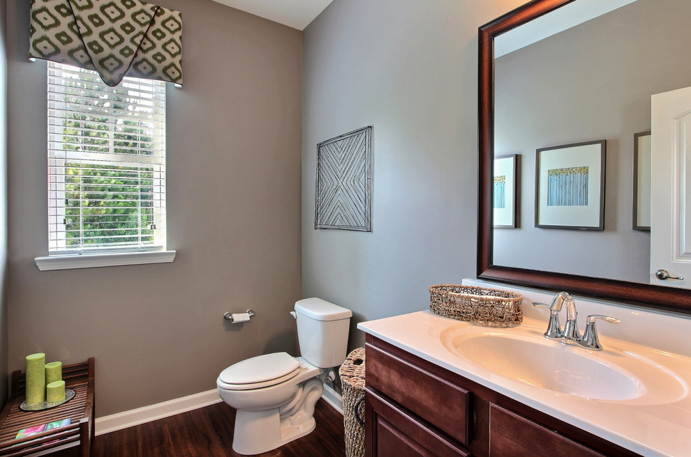 This is an example of a large classic cloakroom in Atlanta with a one-piece toilet, laminate floors, an integrated sink, marble worktops, shaker cabinets, dark wood cabinets, grey tiles, grey walls and brown floors.