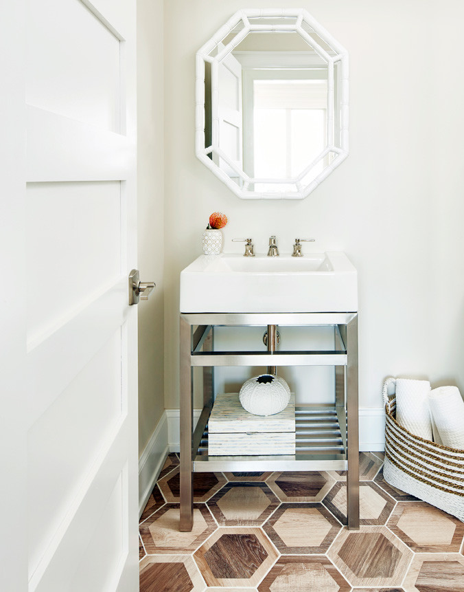 Example of a small beach style porcelain tile and brown floor powder room design in New York with white walls and a console sink