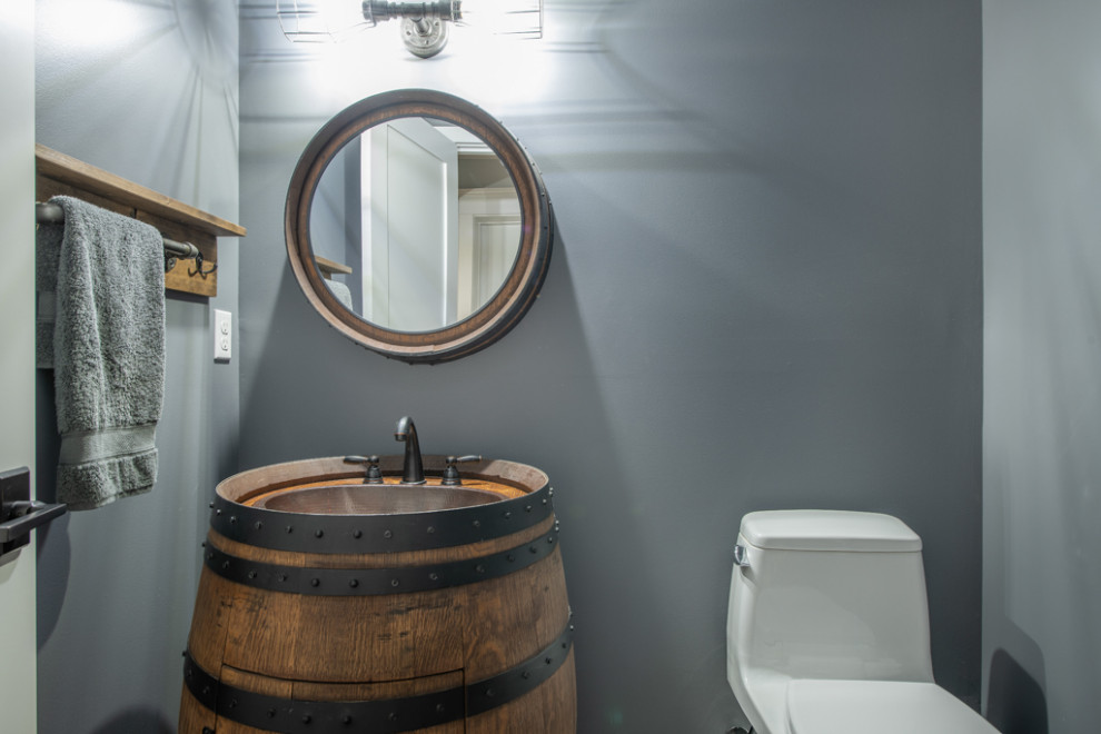 Kleine Urige Gästetoilette mit braunen Schränken, Toilette mit Aufsatzspülkasten, grauer Wandfarbe, braunem Holzboden, Einbauwaschbecken, buntem Boden und freistehendem Waschtisch in Seattle