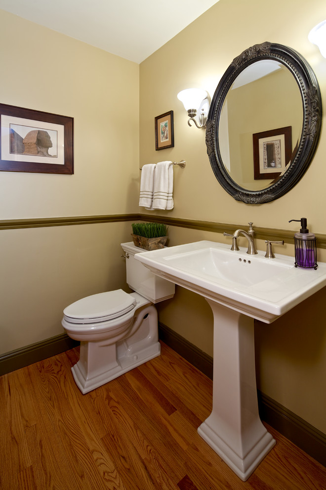 Klassische Gästetoilette mit Sockelwaschbecken, Wandtoilette mit Spülkasten, bunten Wänden und braunem Holzboden in San Diego