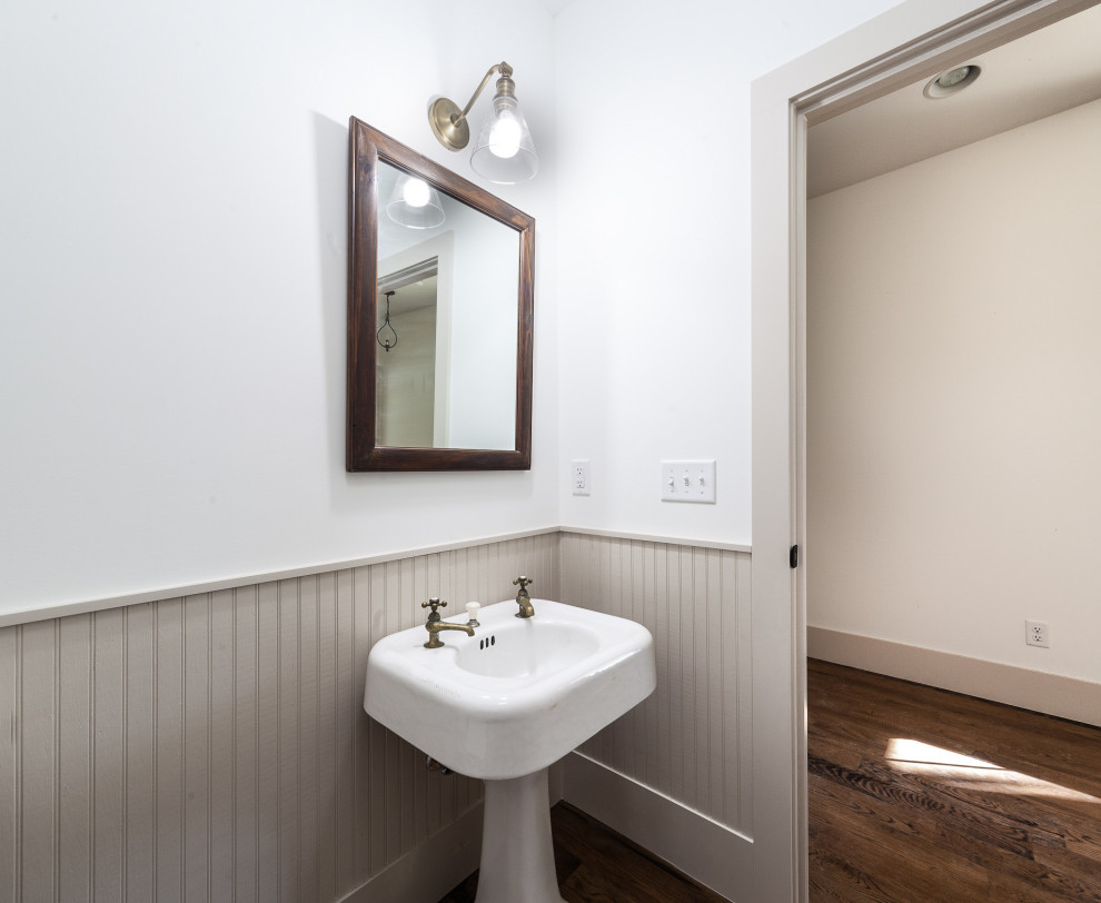 Inredning av ett lantligt mellanstort toalett, med vita väggar, mörkt trägolv, ett piedestal handfat och brunt golv