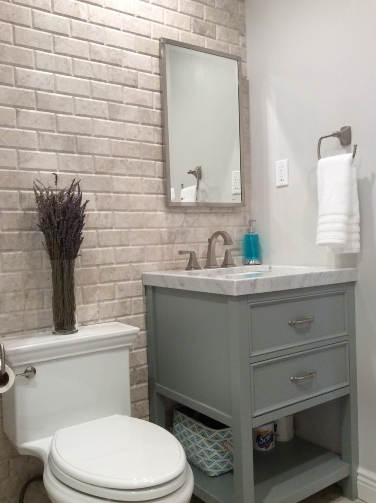 ニューヨークにあるラスティックスタイルのおしゃれなトイレ・洗面所 (家具調キャビネット、一体型トイレ	、白いタイル、サブウェイタイル、グレーの壁、一体型シンク、大理石の洗面台、グレーのキャビネット) の写真