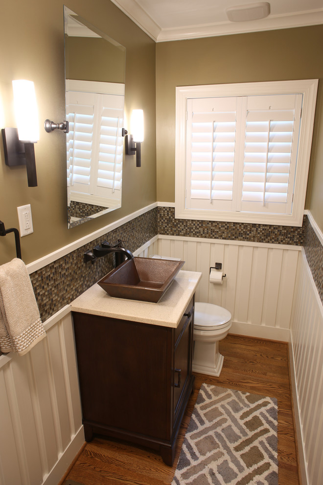 Example of a mid-sized arts and crafts mosaic tile and brown tile light wood floor powder room design in Charlotte with furniture-like cabinets, dark wood cabinets, a two-piece toilet, a vessel sink and quartz countertops