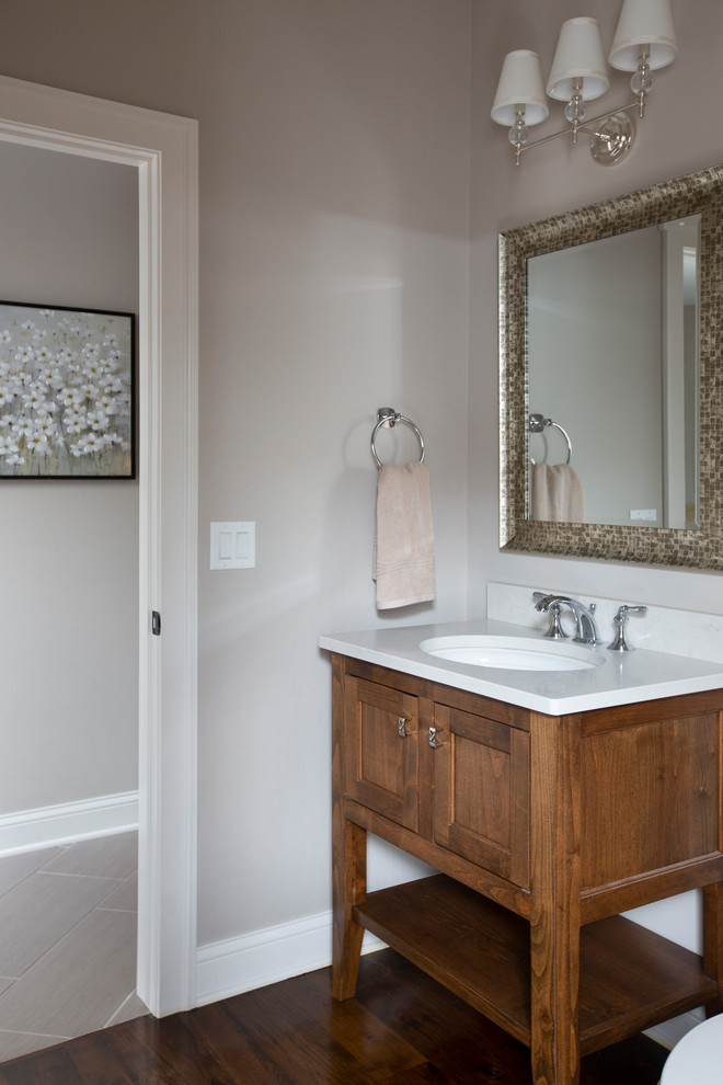 Cette image montre un petit WC et toilettes craftsman en bois brun avec un placard à porte plane, un mur gris, parquet foncé, un lavabo encastré, un plan de toilette en quartz modifié, un sol marron et un plan de toilette gris.