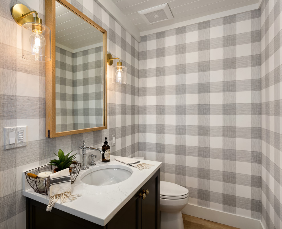 Small farmhouse cloakroom in Portland with shaker cabinets, black cabinets, a two-piece toilet, multi-coloured walls, light hardwood flooring, a submerged sink, quartz worktops, beige floors and white worktops.